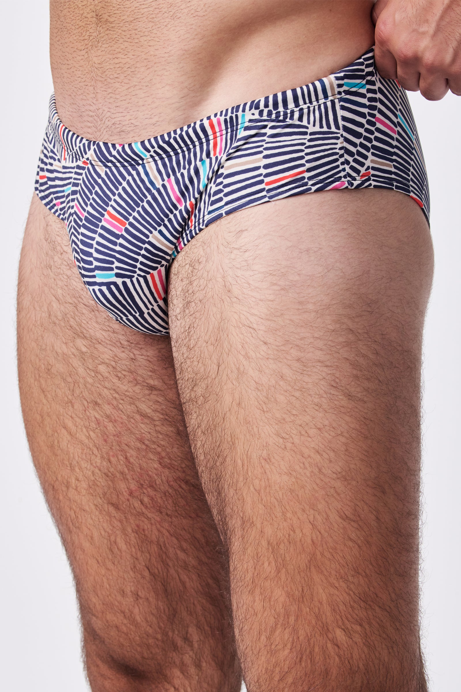 A close-up of a person wearing the Bondi Swim Trunk, featuring navy blue and white stripes with small colorful accents, photographed from hip to mid-thigh against a plain background.