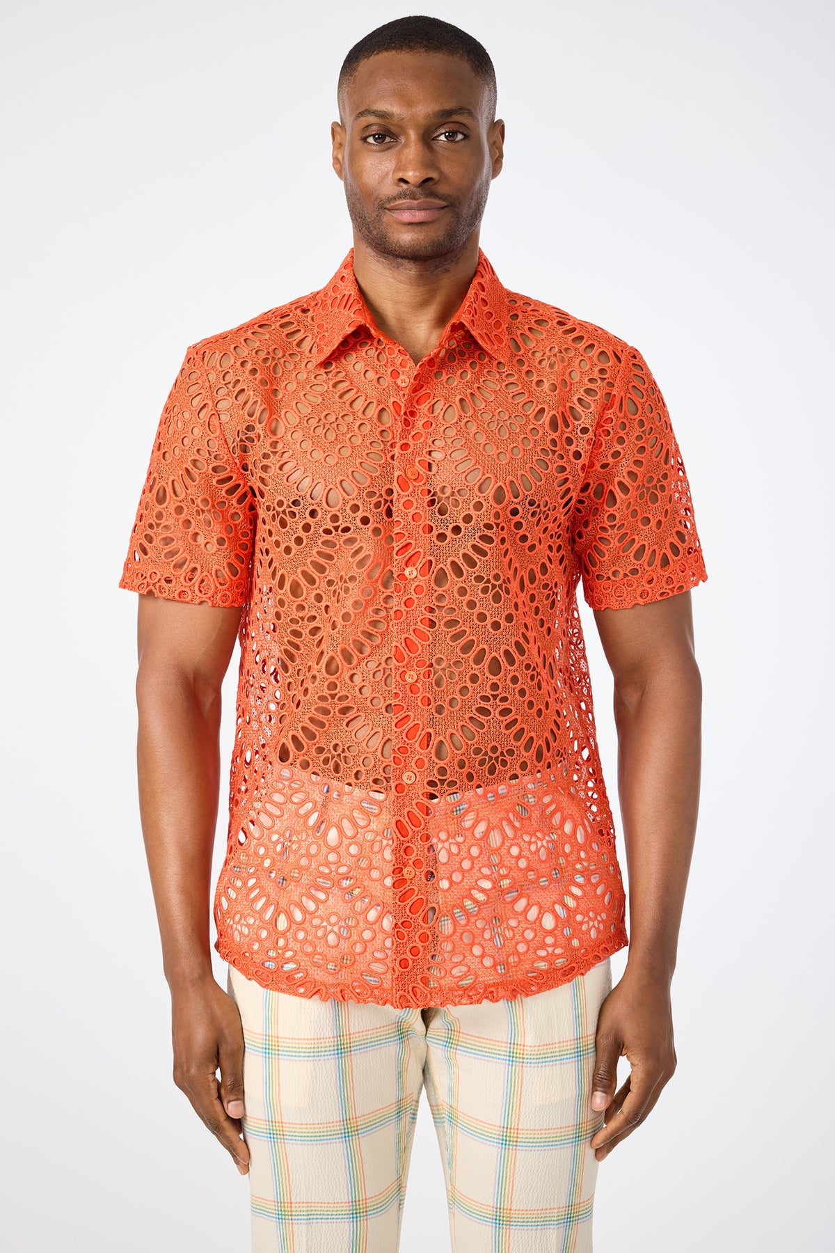 A man wearing the Long Beach Short-Sleeve Shirt in bright orange with a lace pattern and light plaid pants stands against a plain white background.
