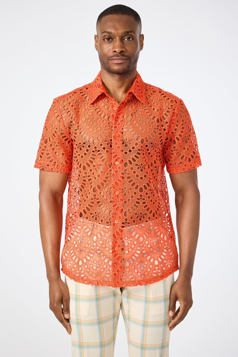 A man wearing the Long Beach Short-Sleeve Shirt in bright orange with a lace pattern and light plaid pants stands against a plain white background.