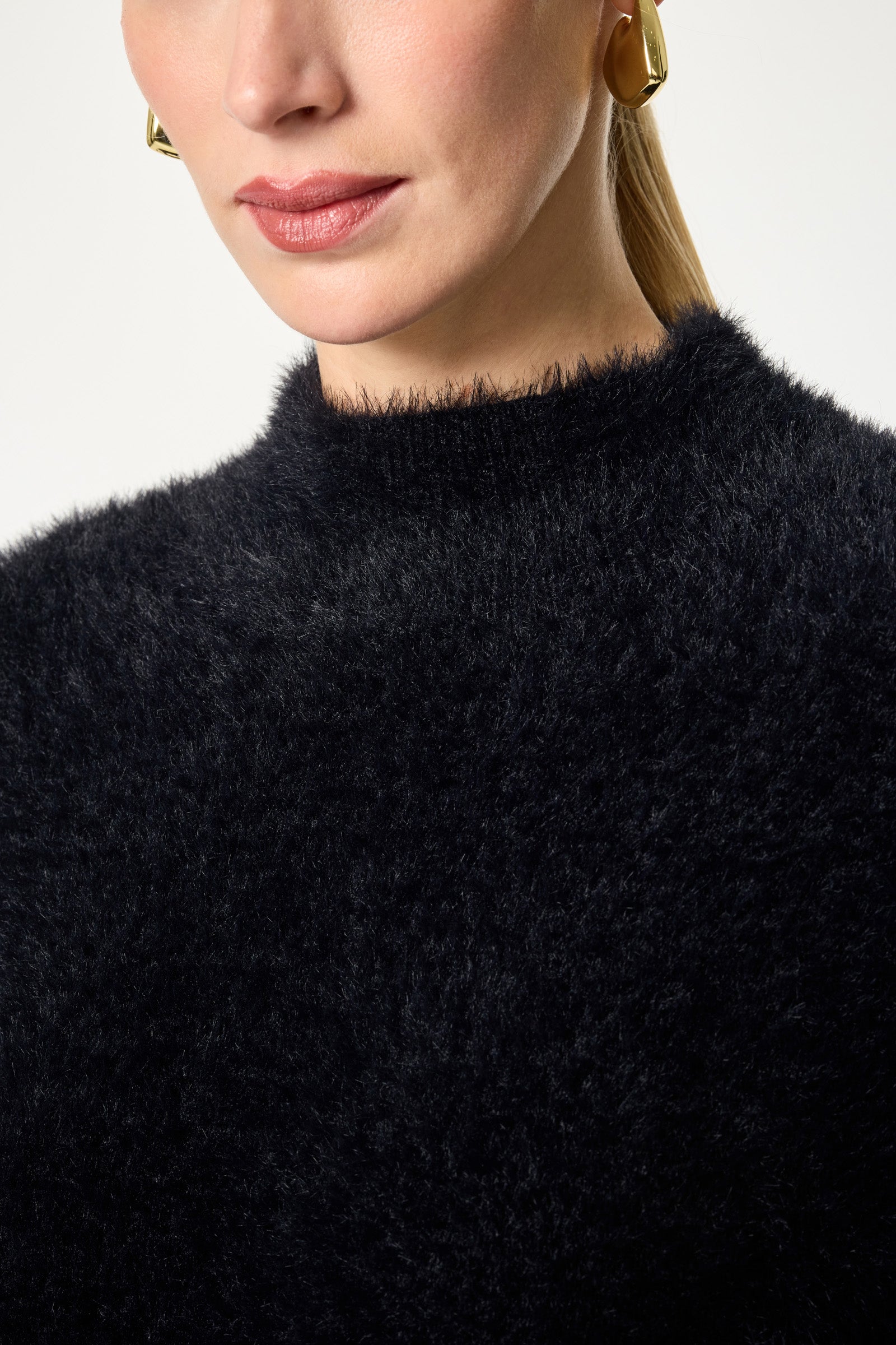 Close-up of a woman wearing gold hoop earrings and the Bazaar Mock Neck Sweater, her hair pulled back and only the lower half of her face visible.