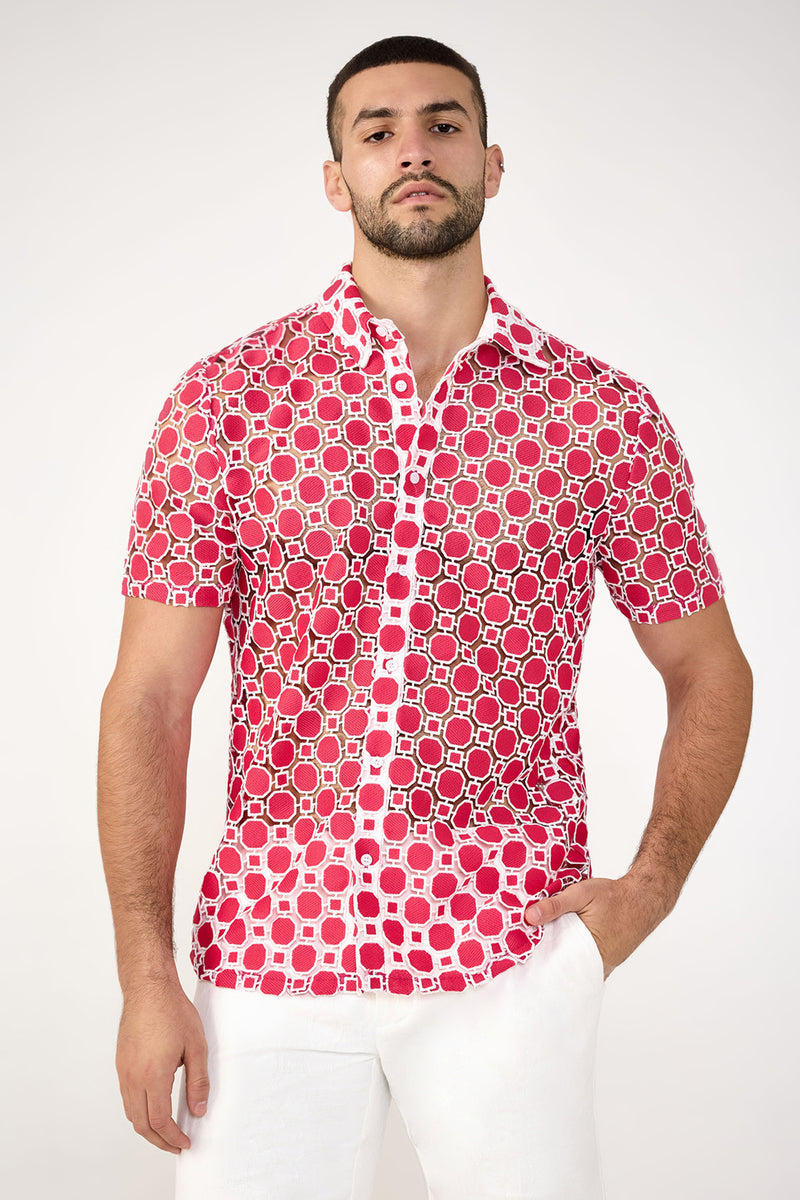 A man with short hair and a beard wears the Long Beach Short-Sleeve Shirt in Cannes Coral and white pants, standing against a plain light background.
