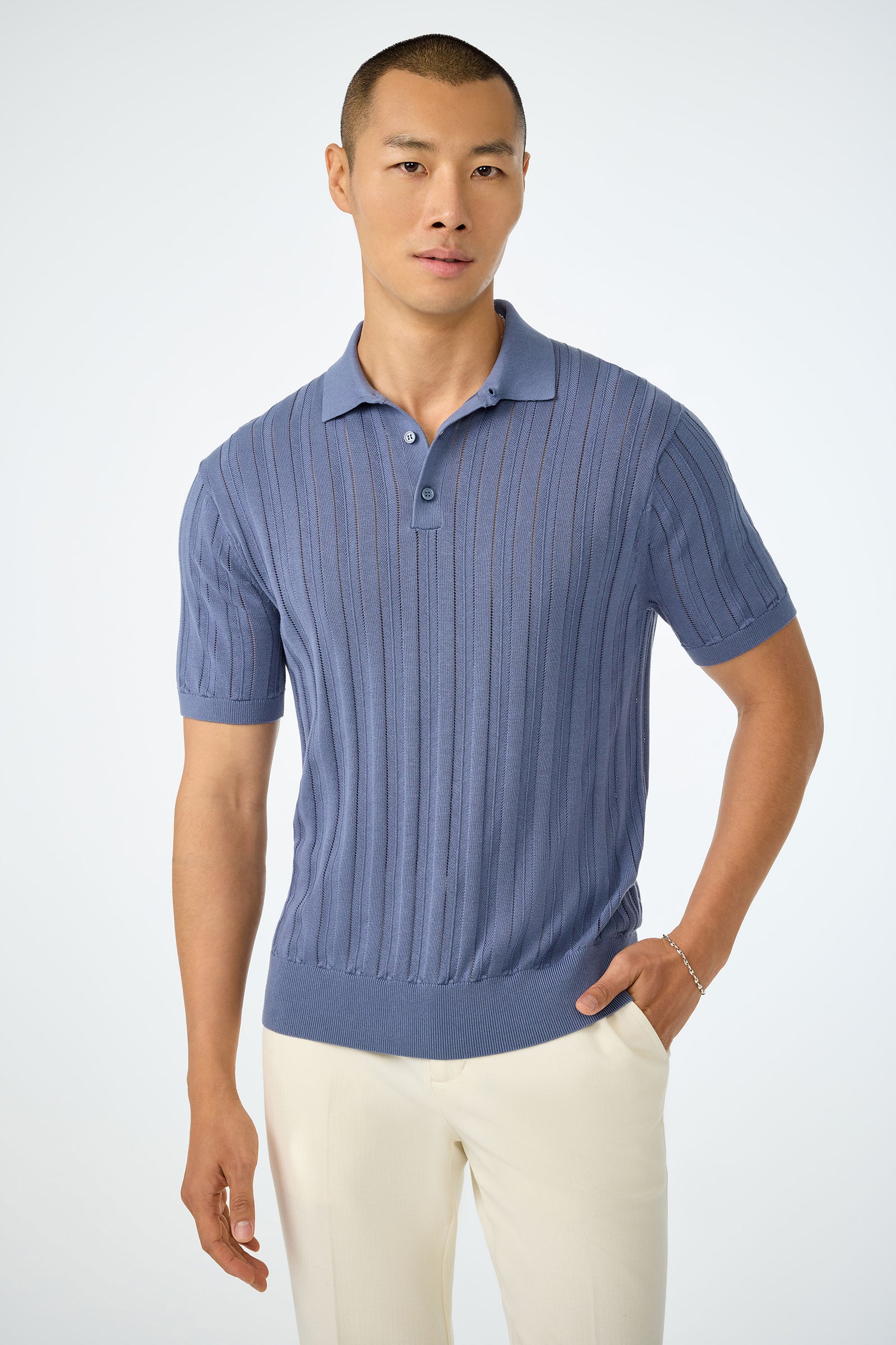 A person stands against a plain background wearing the Kensington Short-Sleeve Polo in Pewter and white pants, with one hand in their pocket and a neutral expression.