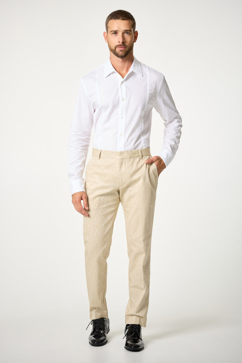 A man stands facing forward against a plain white background, wearing the Baleri Tux Shirt, beige textured trousers, and black dress shoes. One hand is in his pocket and he maintains a neutral expression.