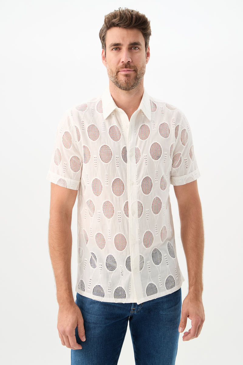 A man with short brown hair and a trimmed beard wears the Branson Shirt - Tennis Eyelet in Whitewash with blue jeans, standing against a plain white background.