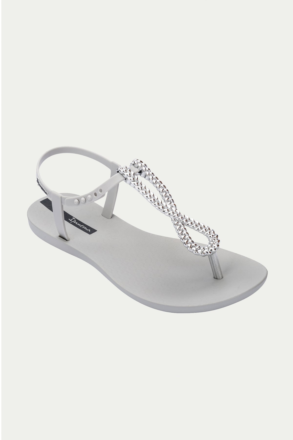 The Ipanema Class Twist Sandal in grey features a toe strap and ankle band, accented with a silver infinity-shaped detail adorned with small rhinestones on the front.