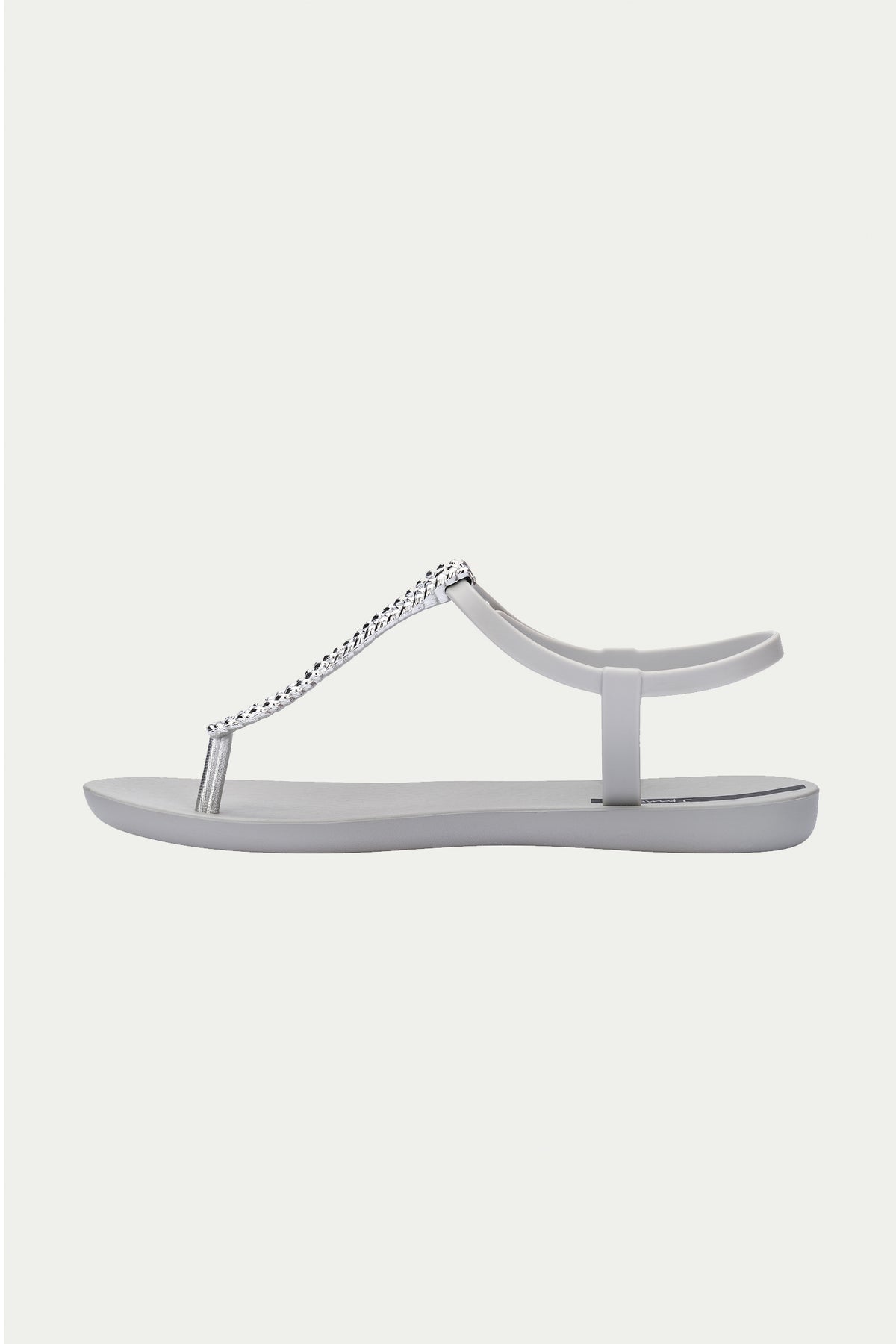 The Ipanema Class Twist Sandal in Grey is a minimalist flat sandal featuring a toe post, ankle strap, and a decorative silver chain detail across the top.