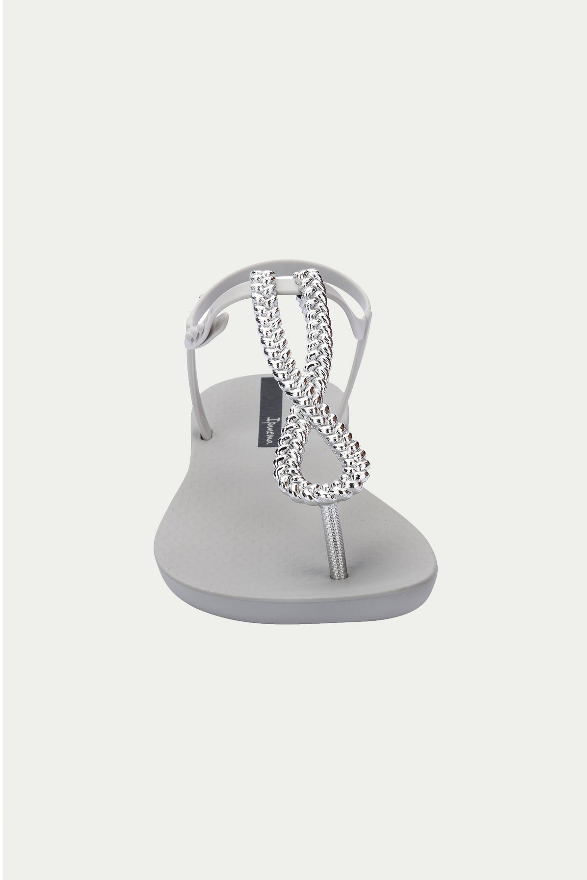 The Ipanema Class Twist Sandal in grey features a T-strap design with a silver, rhinestone-encrusted decorative loop on the upper strap, shown from the front against a plain white background.