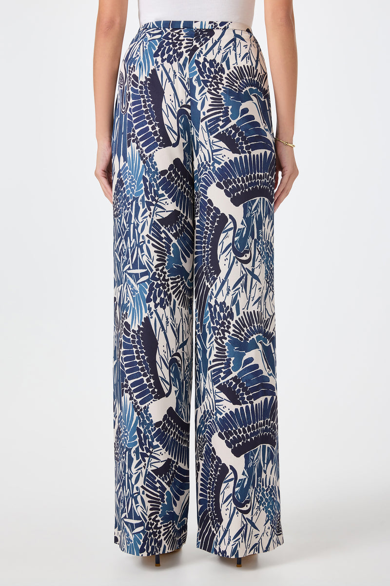 A person wearing the Tavia Wide-Leg Pant - Tsuru, featuring a blue and white crane and foliage print, is shown from the back against a plain white background.