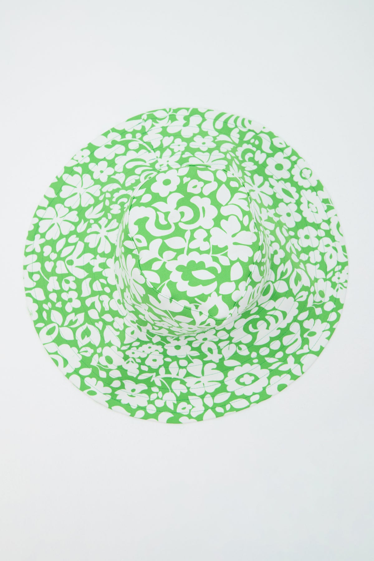 The Shade Packable Sun Hat - Poolside Gossip features a wide brim and a green and white floral pattern, shown from above on a plain white background.