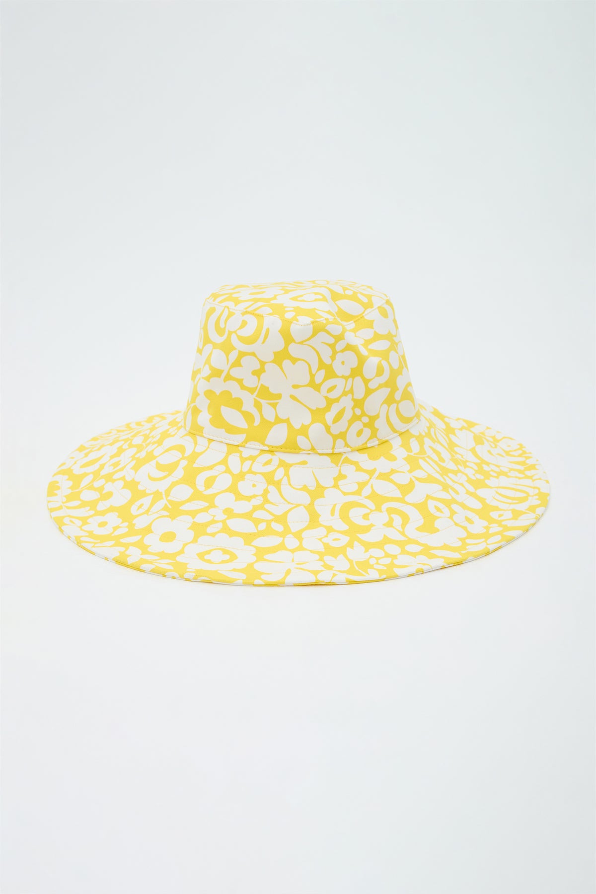 Yellow bucket hat with white floral pattern on a light gray background