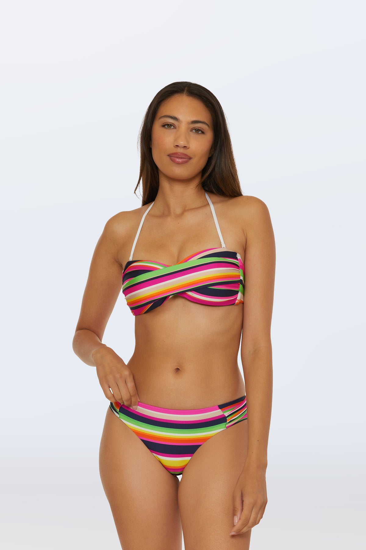 A woman with long dark hair and a neutral expression models the Twist Bandeau Swim Top - Splash Stripe and matching bottoms against a light background, one hand resting near her hip.
