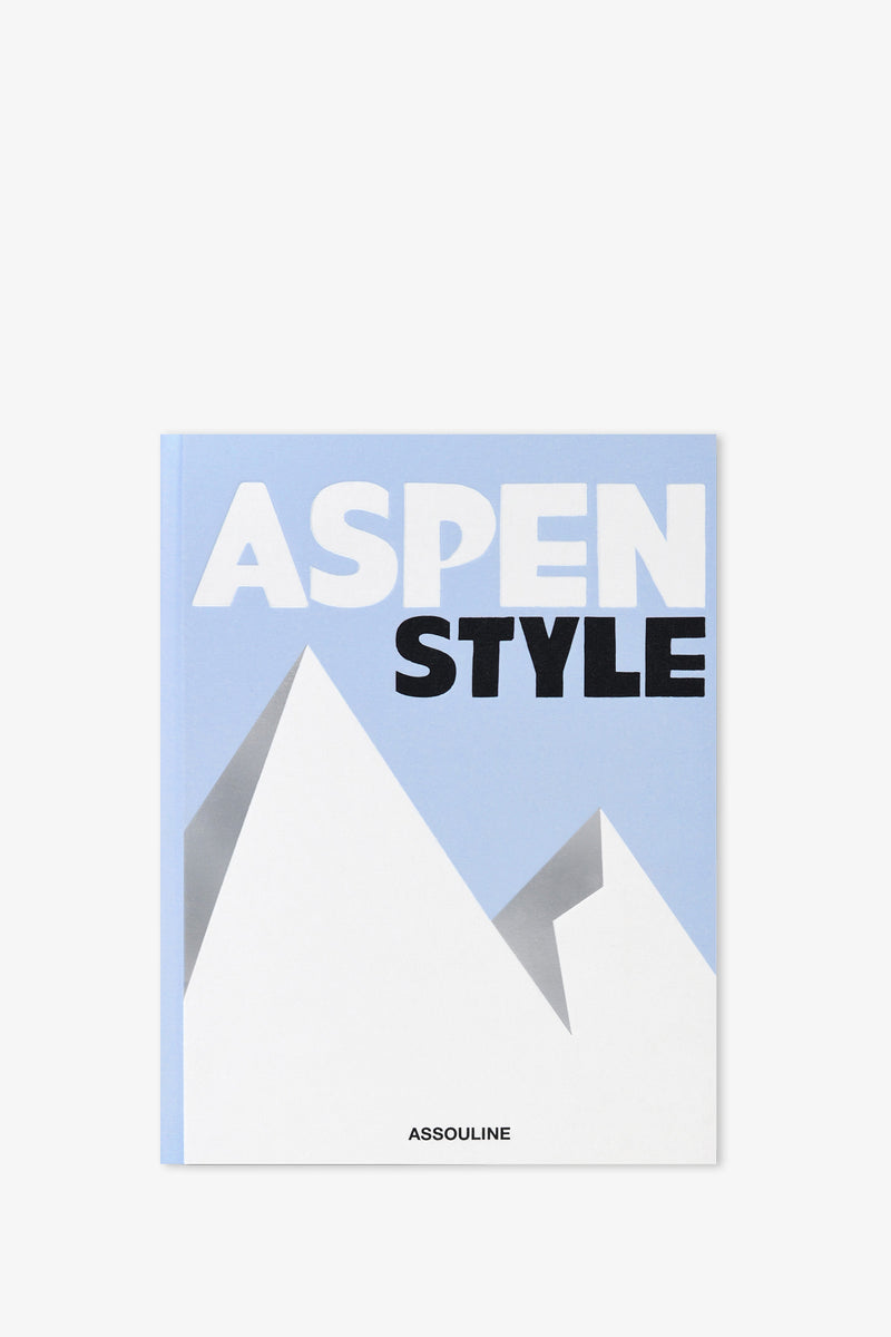The Assouline Aspen Style Book features a blue and white cover with stylized, geometric mountain shapes and the publisher’s name, Assouline, printed at the bottom.