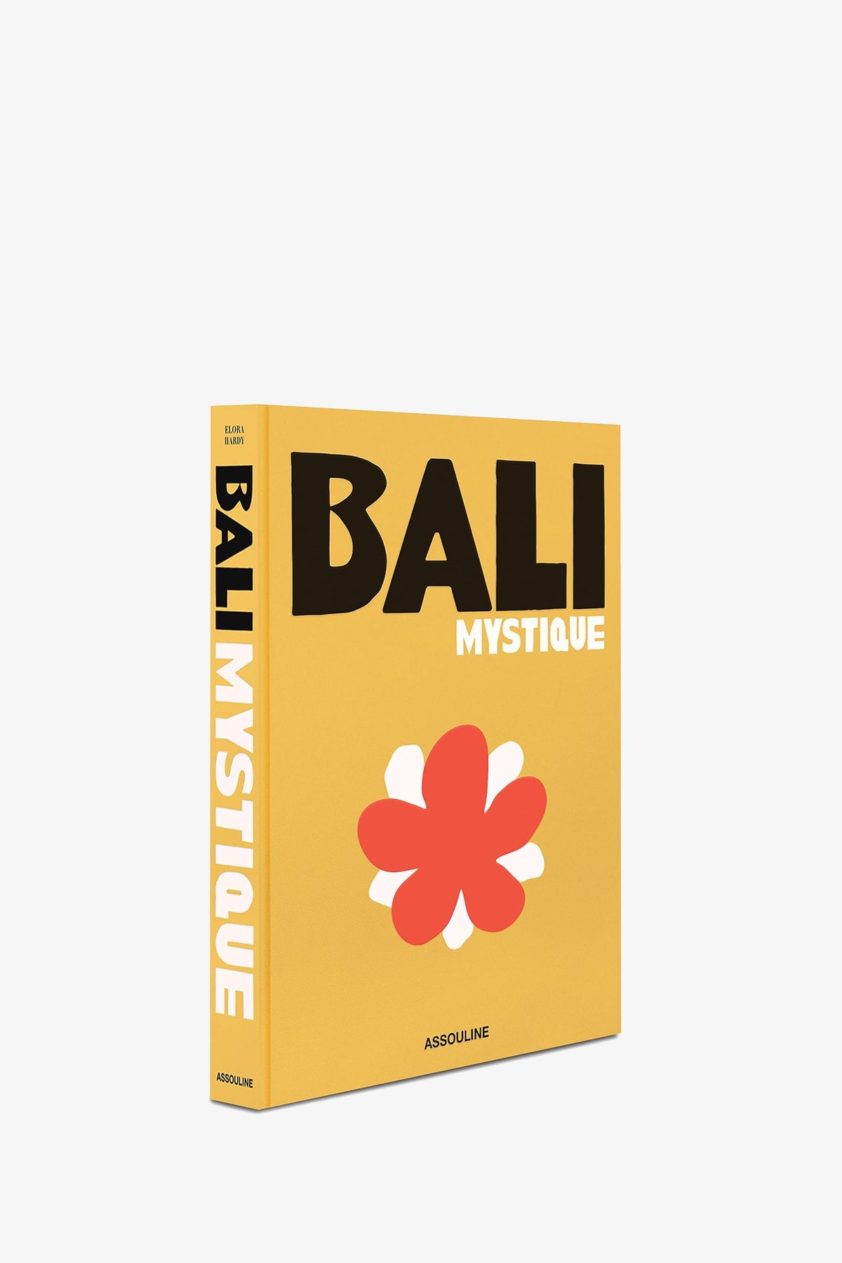 A yellow book titled ASSOULINE BALI MYSTIQUE featuring a large red and white flower on the cover, with the title also appearing on the spine and Assouline printed at the bottom.