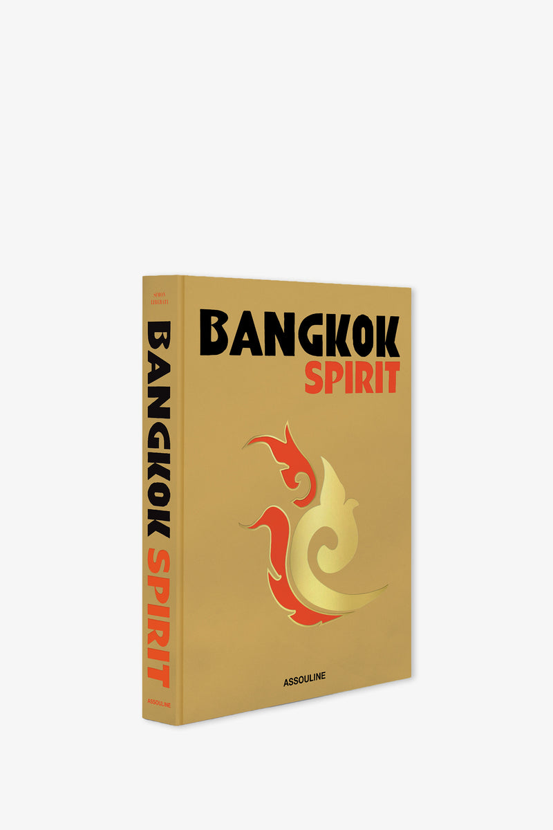 The Assouline Bangkok Spirit Book features a gold cover adorned with bold black and red lettering and a striking red and gold stylized phoenix design. The spine is visible, along with the publisher's name, Assouline.