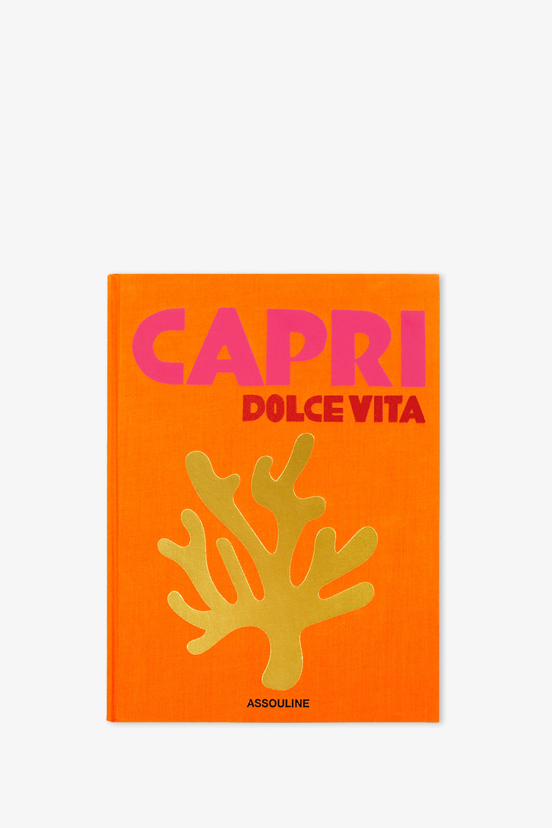 An orange book cover for the Assouline Capri Dolce Vita Book, featuring the title in pink and red lettering, a gold coral illustration beneath the title, and the publisher’s name, Assouline, at the bottom.