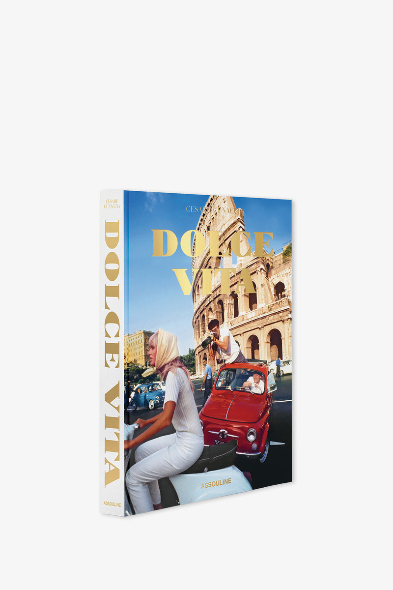 Assouline Dolce Vita Book featuring a cover with a woman riding a scooter and a man driving a red convertible near the Colosseum in Rome, set against a bright and sunny backdrop that captures the essence of classic Italian life.