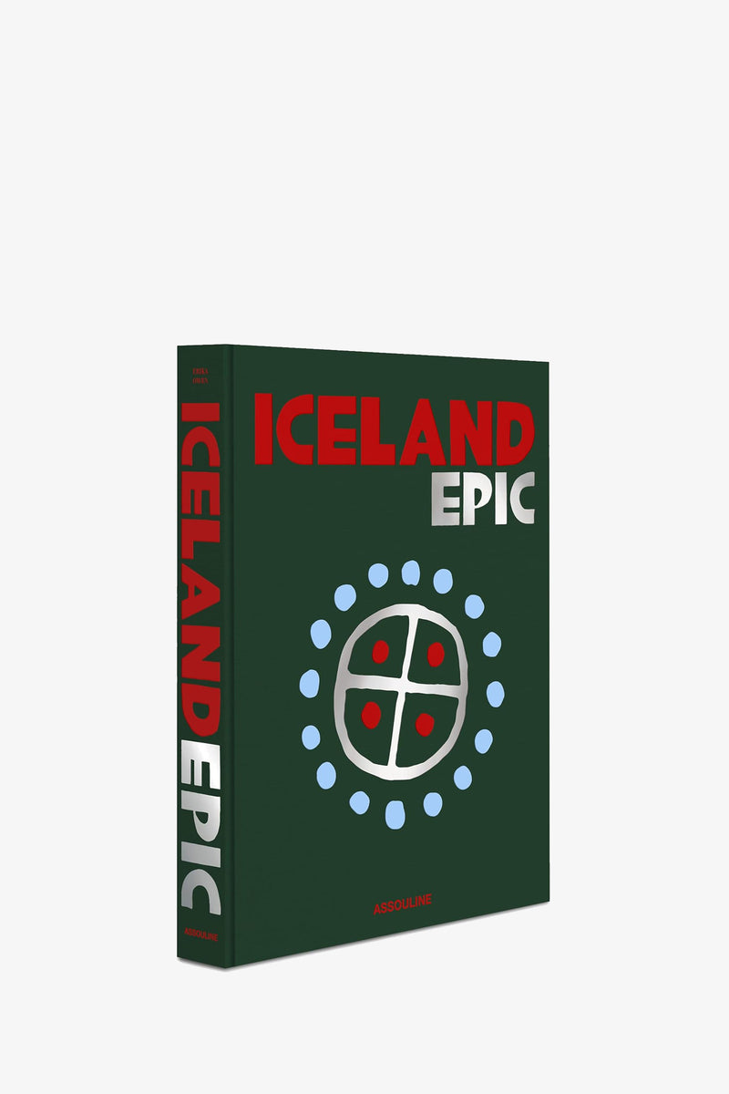 The Assouline Iceland Epic Book features bold red and white text on a dark green cover, adorned with a circular abstract design of blue dots and a cross pattern. The title is also displayed vertically along the spine.