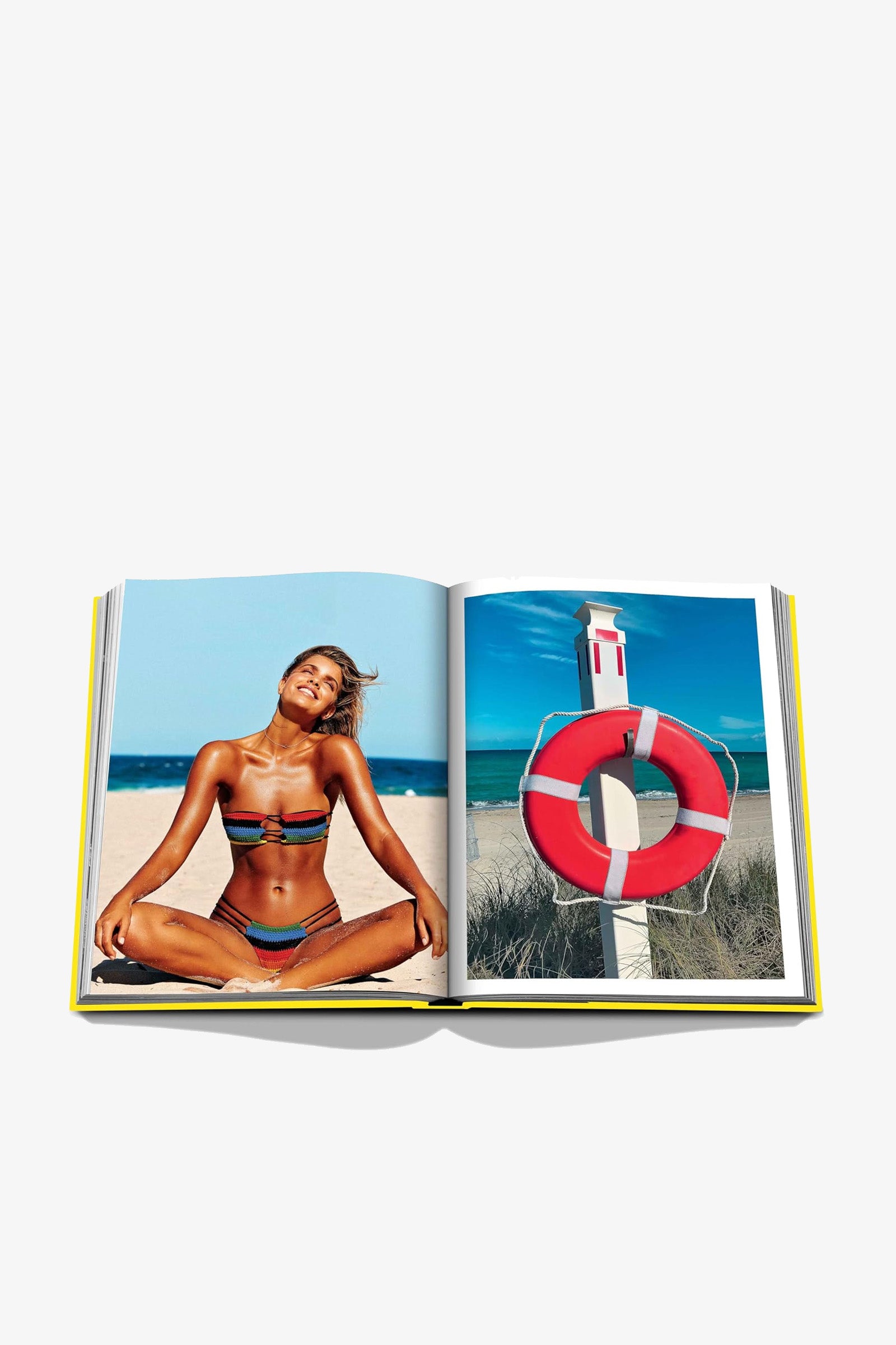 Open Assouline Miami Beach Book displaying a woman in a bikini sitting cross-legged on the beach on the left page and a red lifebuoy on a stand by the ocean on the right page.