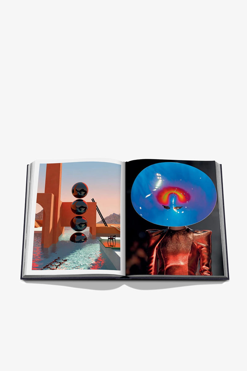An open Assouline Moon Paradise Book displays abstract art: the left page showcases floating spheres above a pool with geometric structures, while the right page features a person in a shiny outfit adorned with a large rainbow-colored circular headpiece.