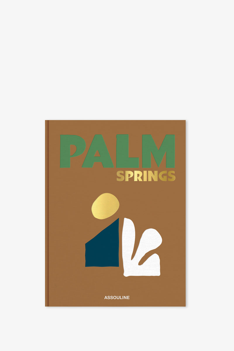 The Assouline Palm Springs Book features a brown cover with bold green and yellow "PALM SPRINGS" text, abstract gold, blue, and white shapes, and "ASSOULINE" printed at the bottom.
