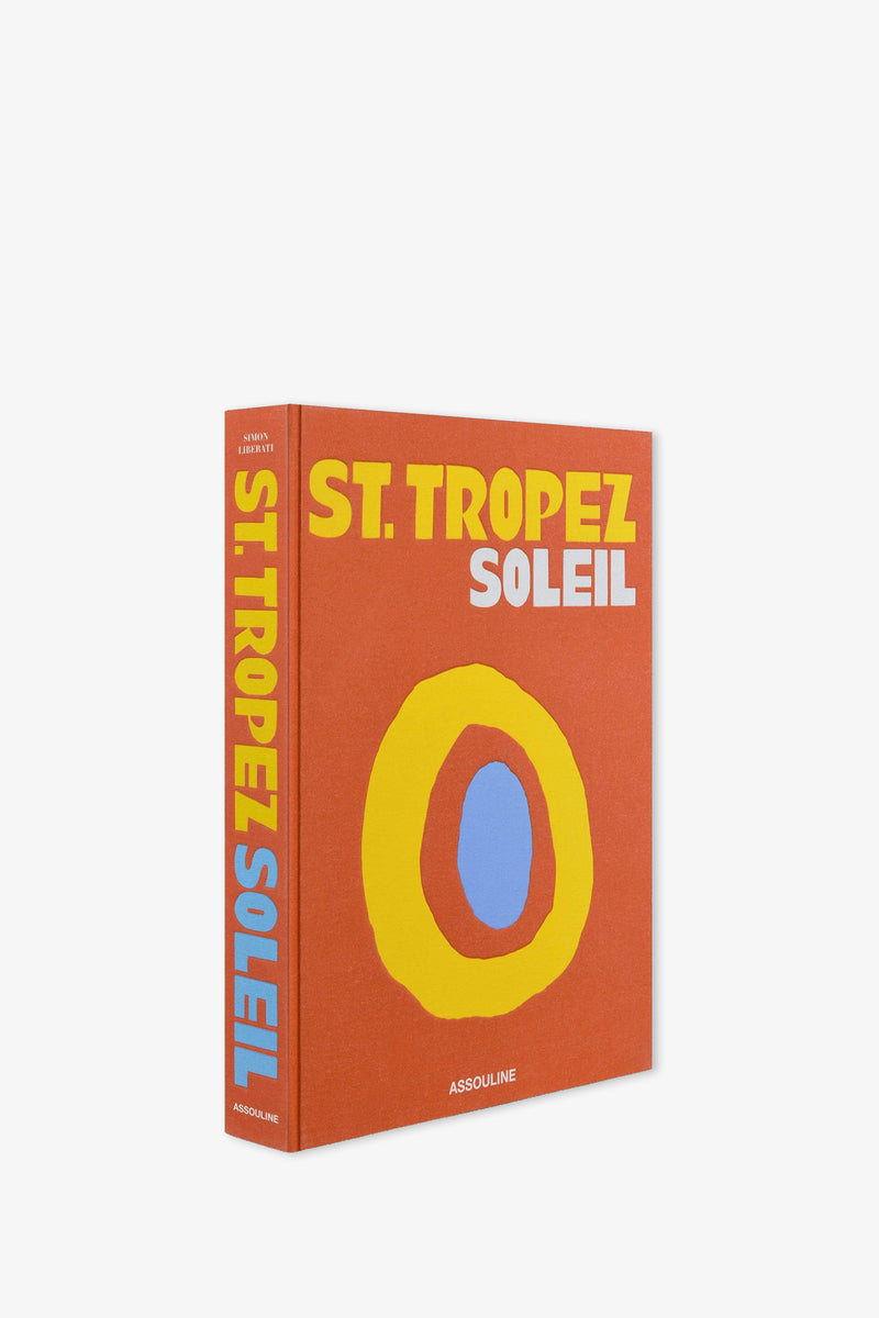 The Assouline St. Tropez Soleil Book features a striking orange cover with prominent yellow and white lettering, accented by an abstract circular design in yellow, red, and blue. The publisher's name, Assouline, is displayed at the bottom.
