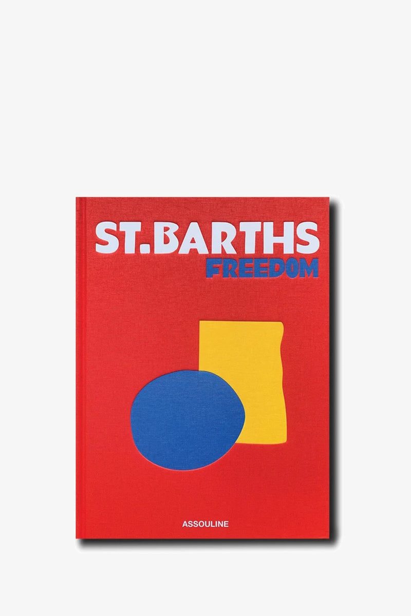 A red book cover for the Assouline St Barths Freedom Book, featuring the title “ST. BARTHS FREEDOM” in white and blue letters, with a blue oval and a yellow irregular shape beneath the title; the publisher name “ASSOULINE” appears at the bottom.