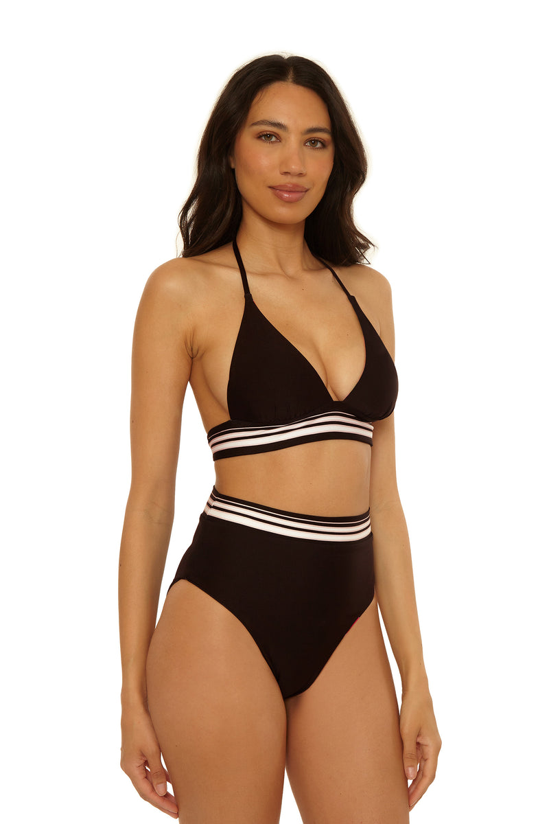A woman with long dark hair models the High-Waist Swim Bottom - Bougainvillea, a black high-waisted bikini bottom with white and pink striped bands, paired with a matching halter top, against a plain white background.