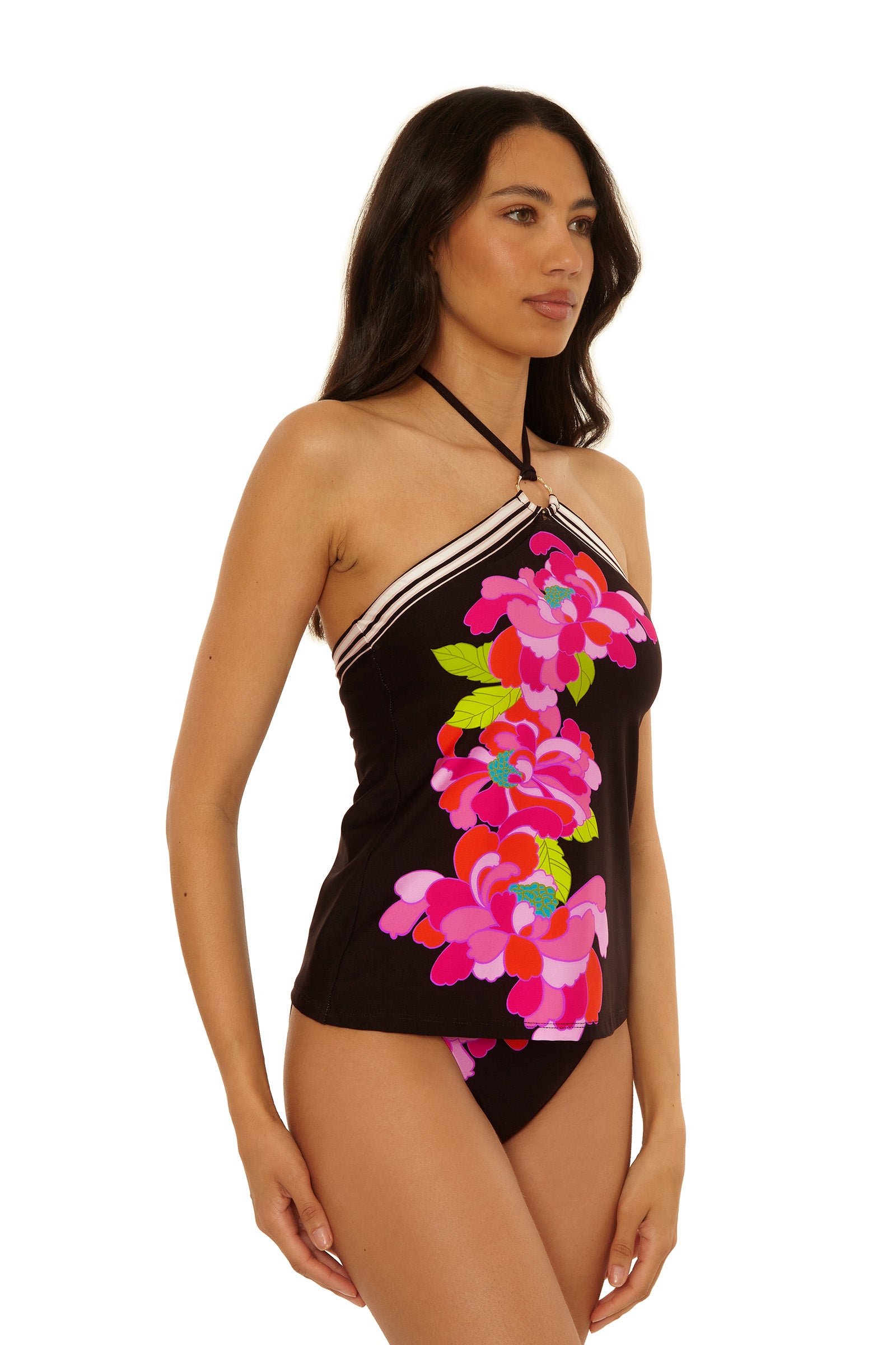 A woman wears the Reversible Tankini Swim Top - Bougainvillea, featuring a black halter-neck style with white trim and a vibrant pink floral pattern, standing against a plain white background.