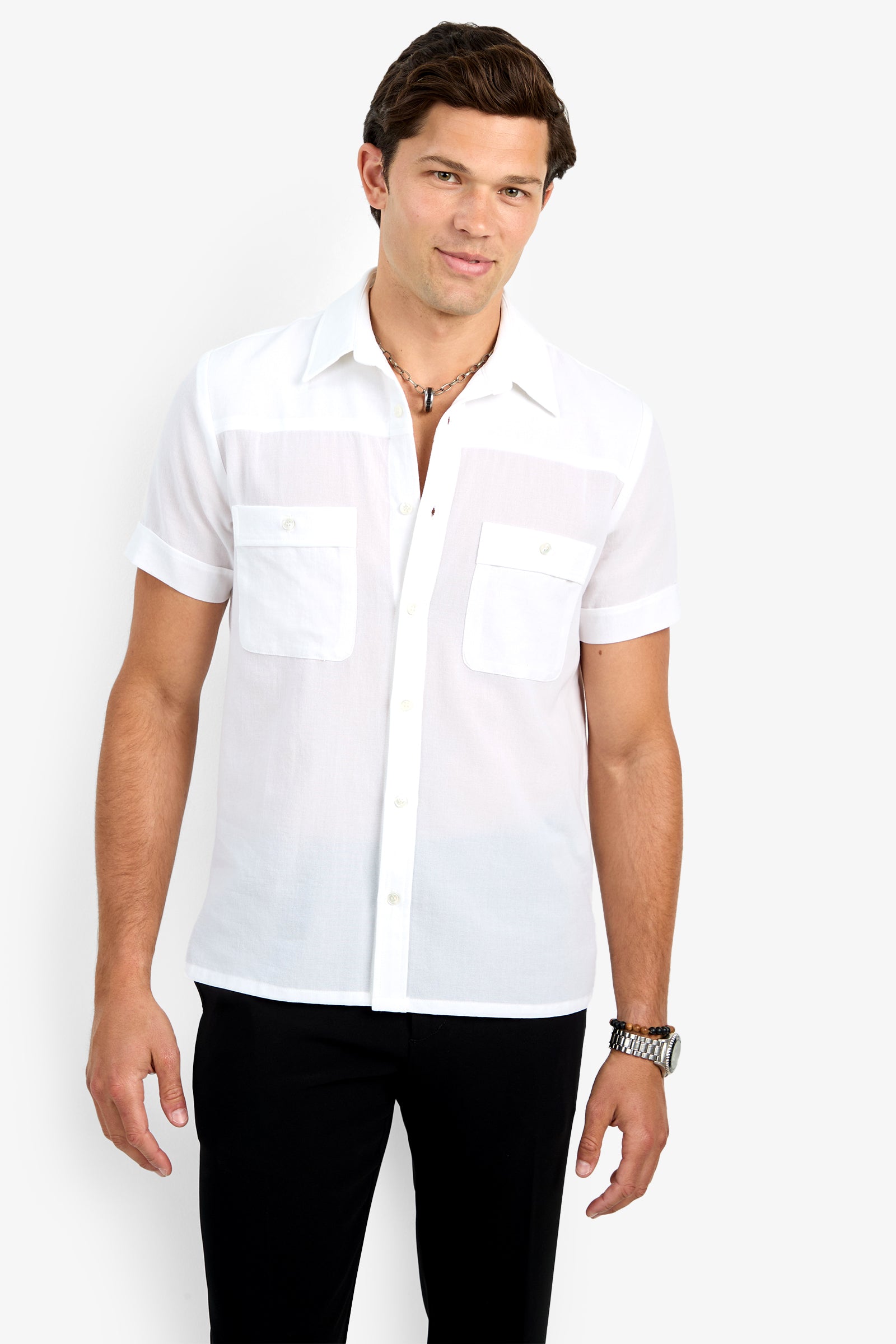 A man with short brown hair is wearing the Will Shirt—a sheer white short-sleeve button-up with two chest pockets—paired with black pants and a watch, standing against a plain white background.