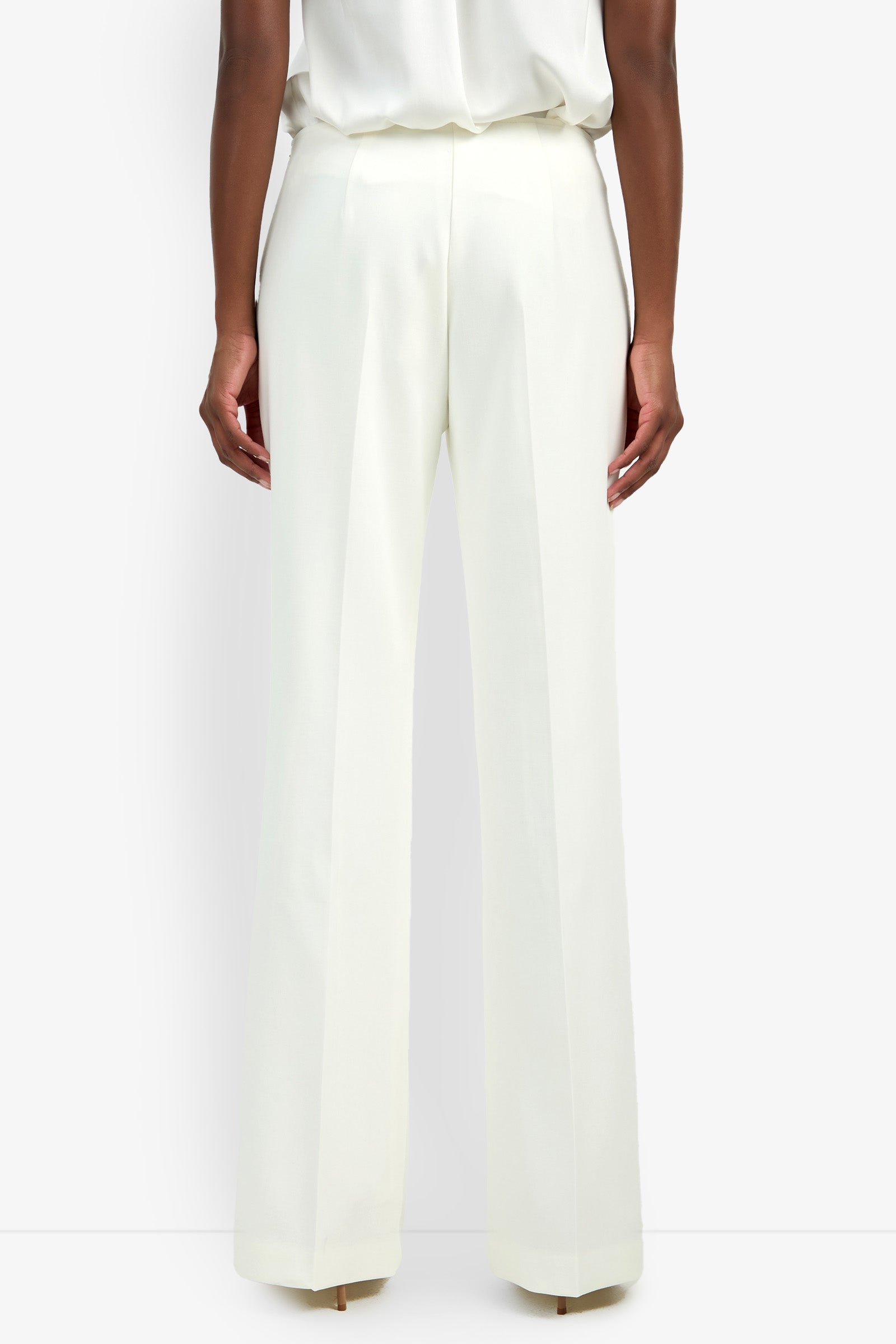 A person shown from the back against a plain white background wears CHIMAYO 2 PANT—high-waisted, wide-leg white pants crafted from a soft viscose blend—with a tucked-in white top.