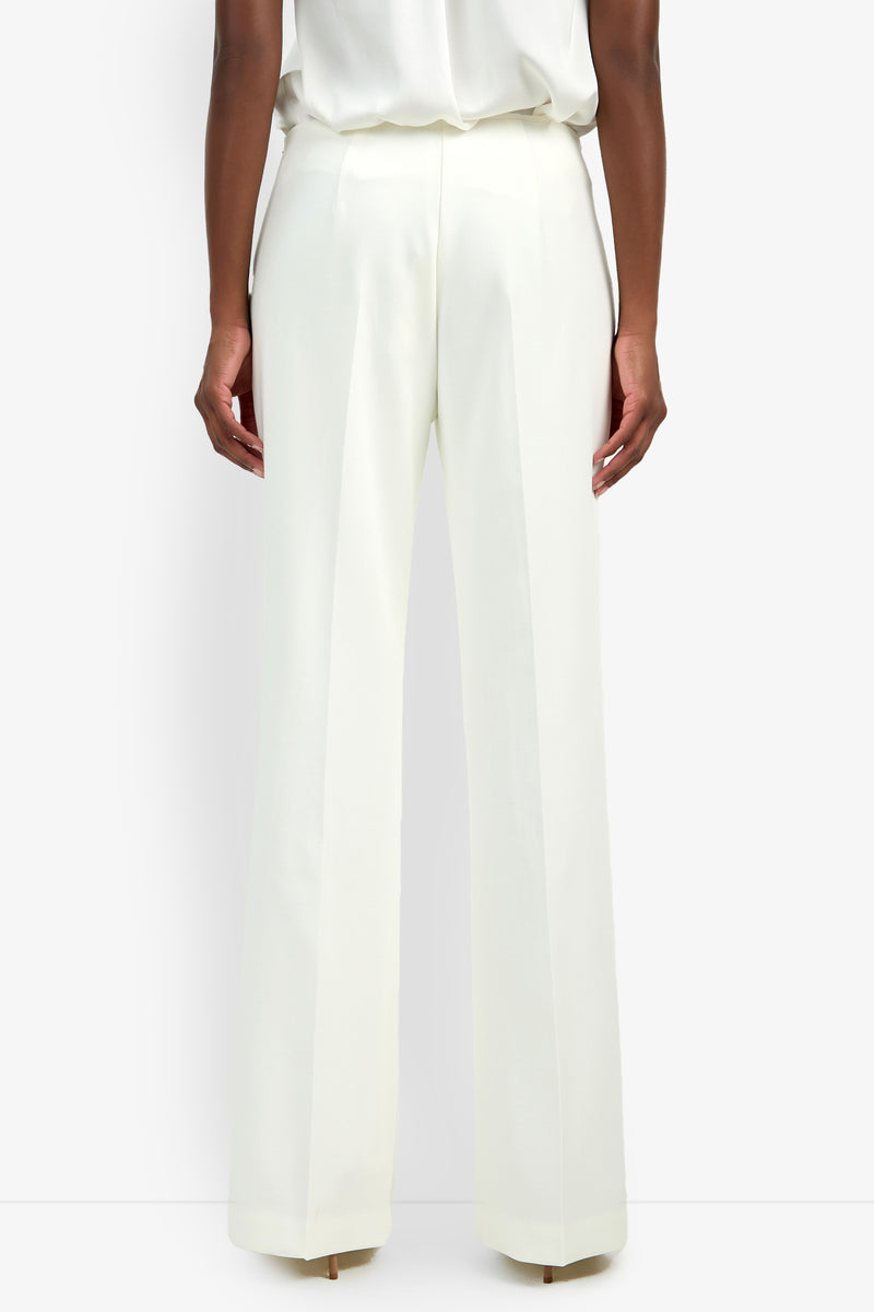 A person shown from the back against a plain white background wears CHIMAYO 2 PANT—high-waisted, wide-leg white pants crafted from a soft viscose blend—with a tucked-in white top.