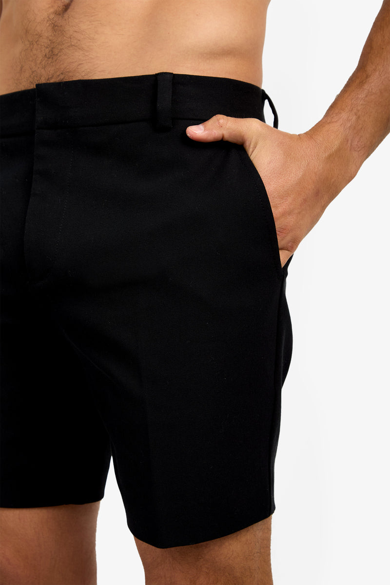 A person models the Lawrence Short in black, with their right hand in the pocket, highlighting a close-up of the shorts and part of their bare torso and arm against a white background.