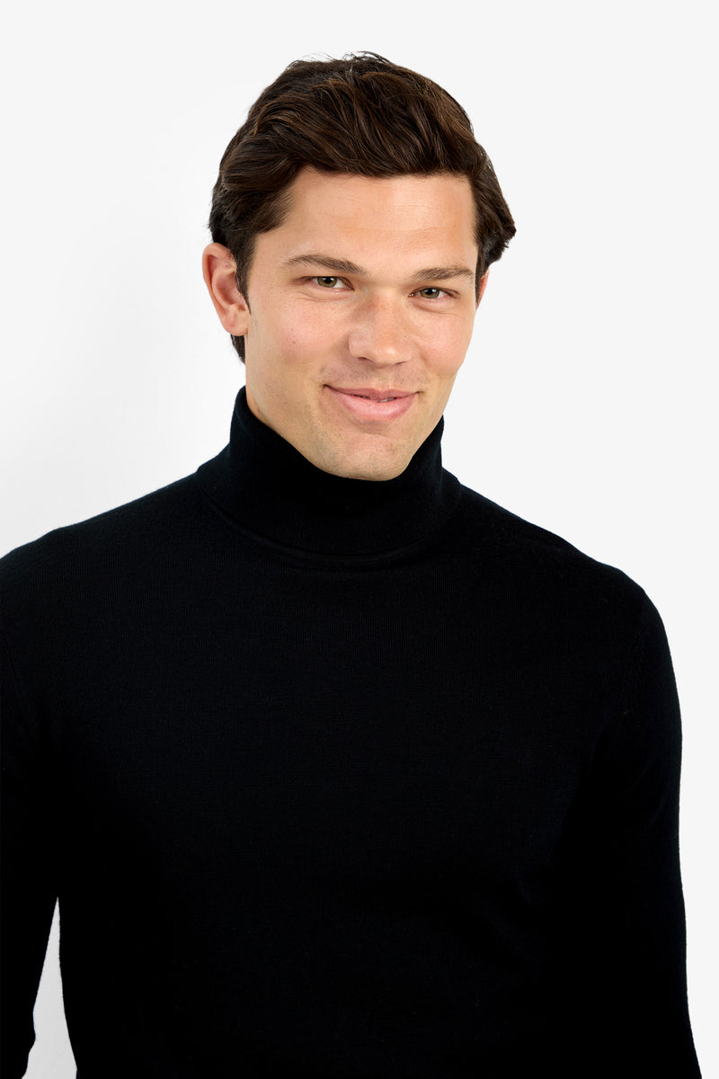 A man with short brown hair softly smiles while wearing the Roy Long Sleeve Turtleneck, standing against a plain white background.