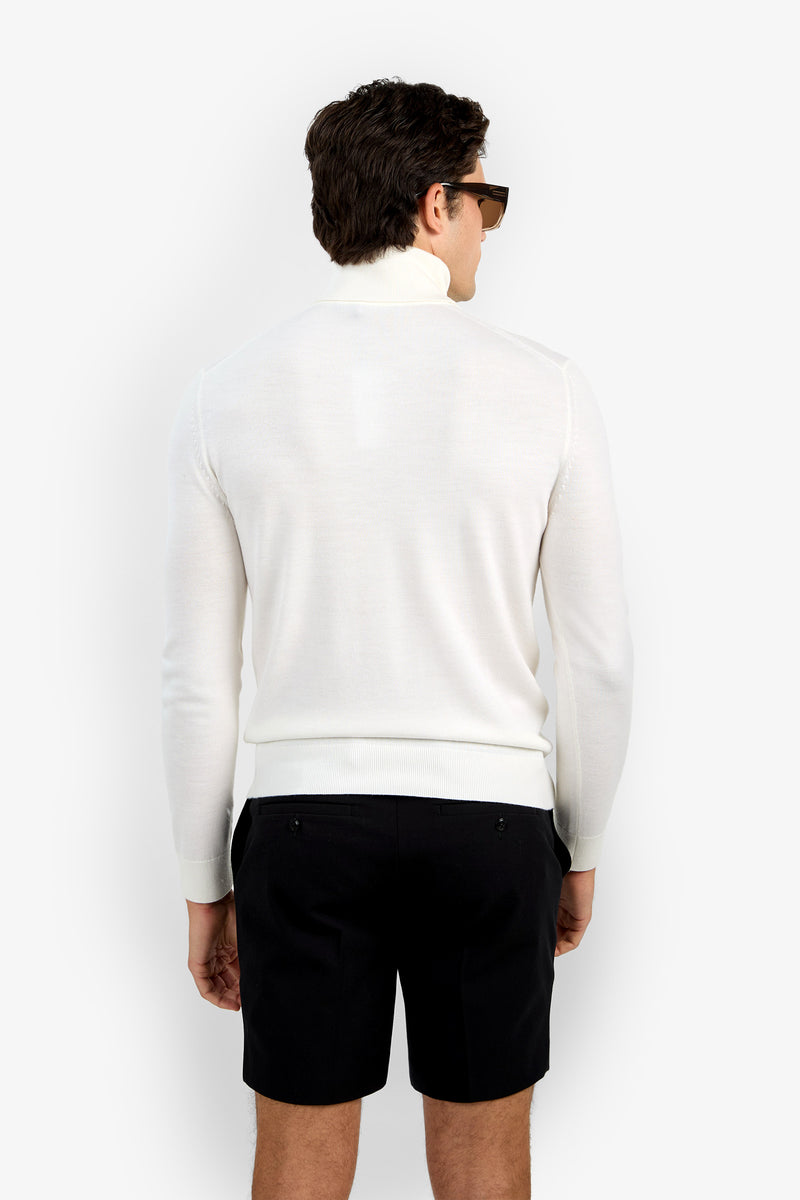 A man with short brown hair, sunglasses, a white Roy Long Sleeve Turtleneck, and black shorts stands facing away from the camera against a plain white background.