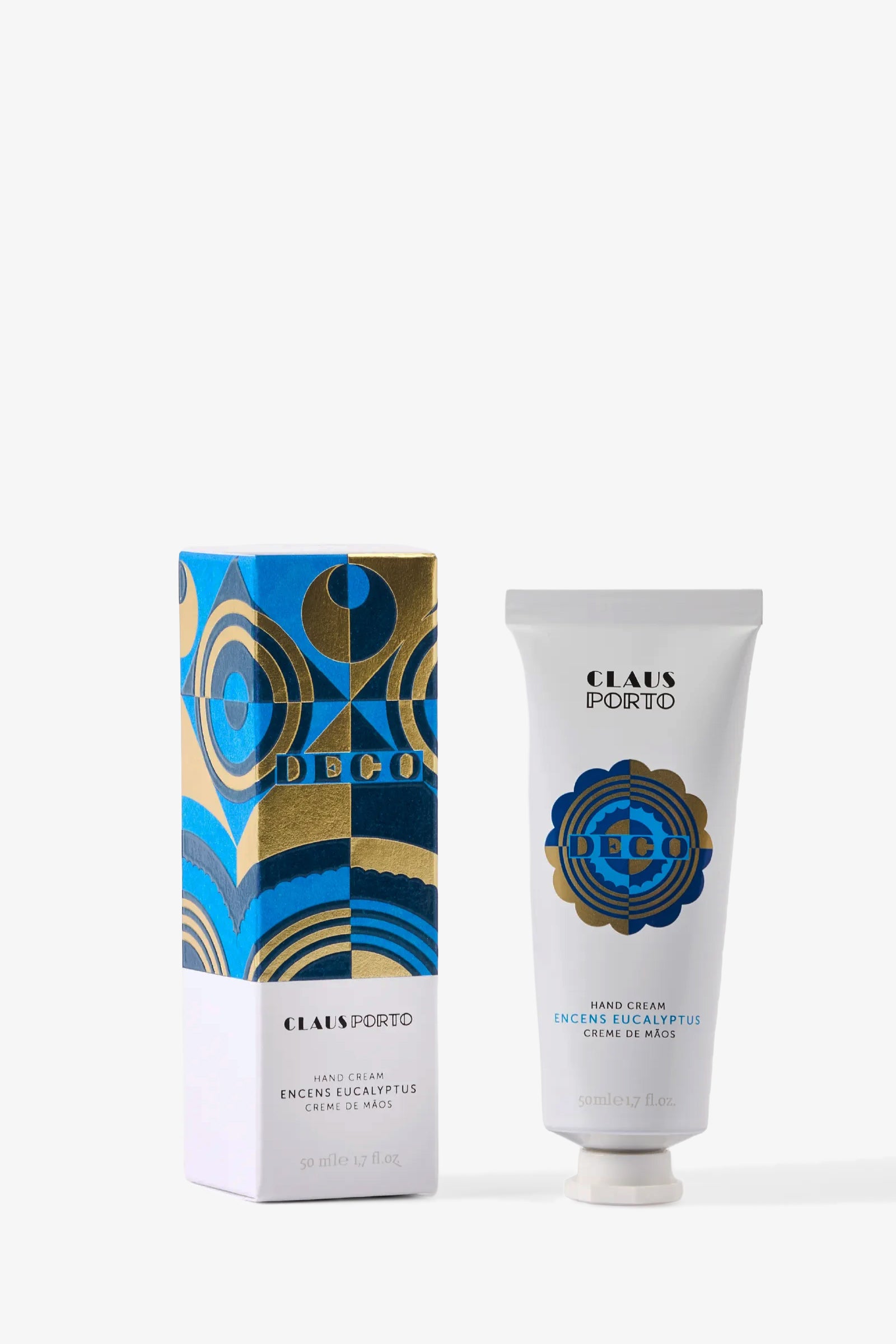 A tube of Claus Porto Deco Hand Cream with eucalyptus stands next to its blue, gold, and white Art Deco-inspired box, both upright against a white background.
