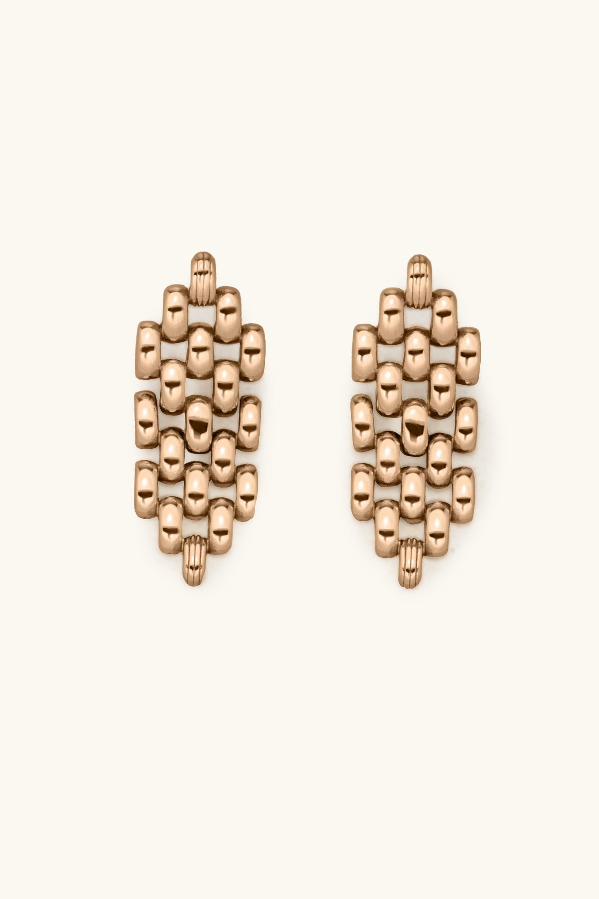 The Phoebe Earrings are gold, featuring a geometric cluster of small, rounded square beads arranged in an oval pattern on a light background.