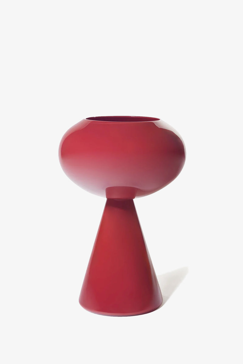 The Fiorelli Concave is a glossy, modern red vase featuring a wide, rounded top and a conical base, displayed against a plain white background.