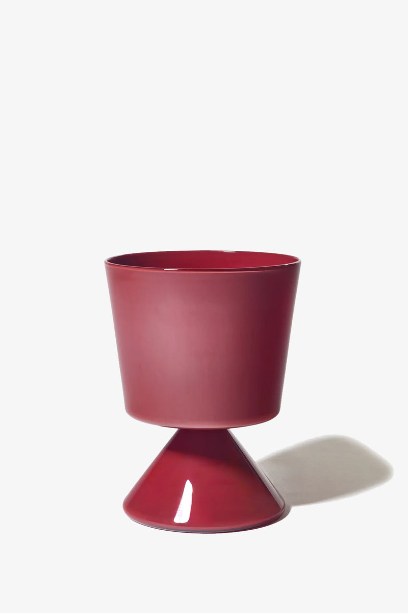 The Fiorelli Low Taper is a modern, glossy red planter featuring a wide, cylindrical top and a cone-shaped base, shown casting a shadow to the right against a plain white background.