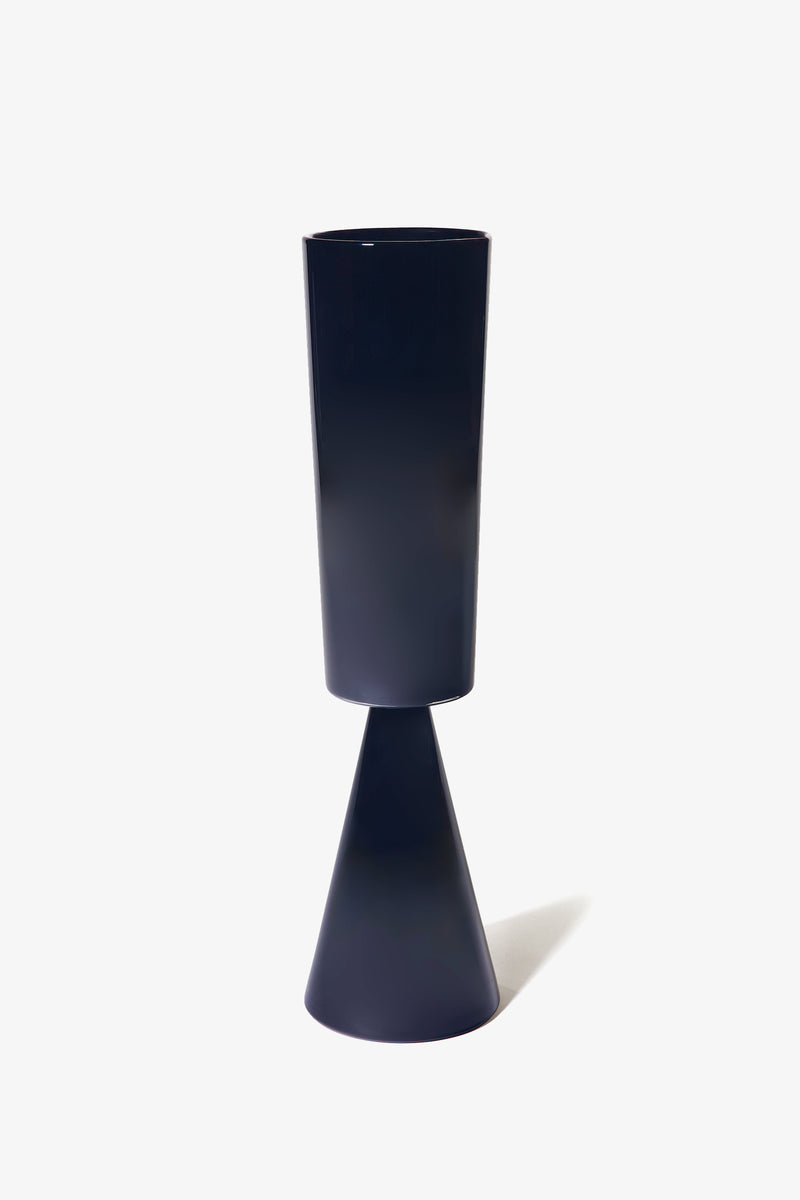 The Fiorelli Tall Cylinder is a modern black vase featuring a cylindrical top and a cone-shaped base, displayed against a plain white background.
