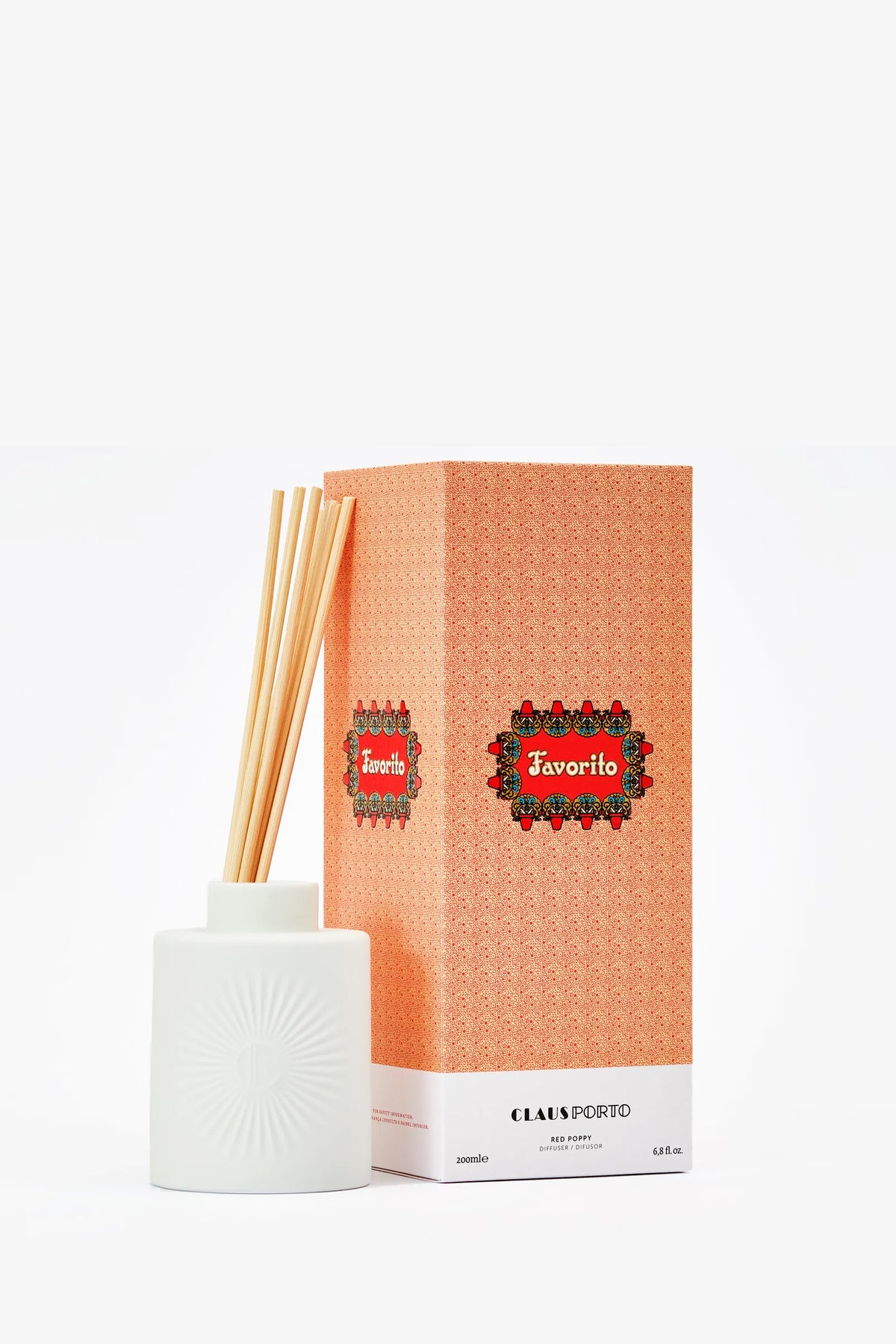 The Claus Porto Favorito Diffuser with reed sticks is displayed next to its patterned orange box on a white background.
