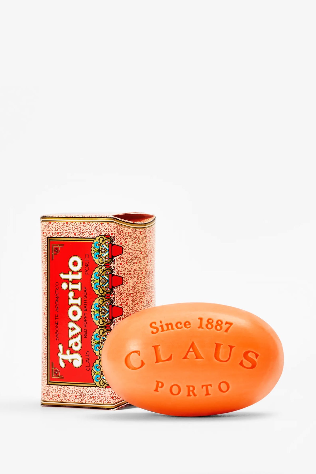 A vibrant orange bar of Claus Porto Favorito Soap, embossed with “Since 1887 CLAUS PORTO,” is displayed beside its ornate red and gold Favorito box.