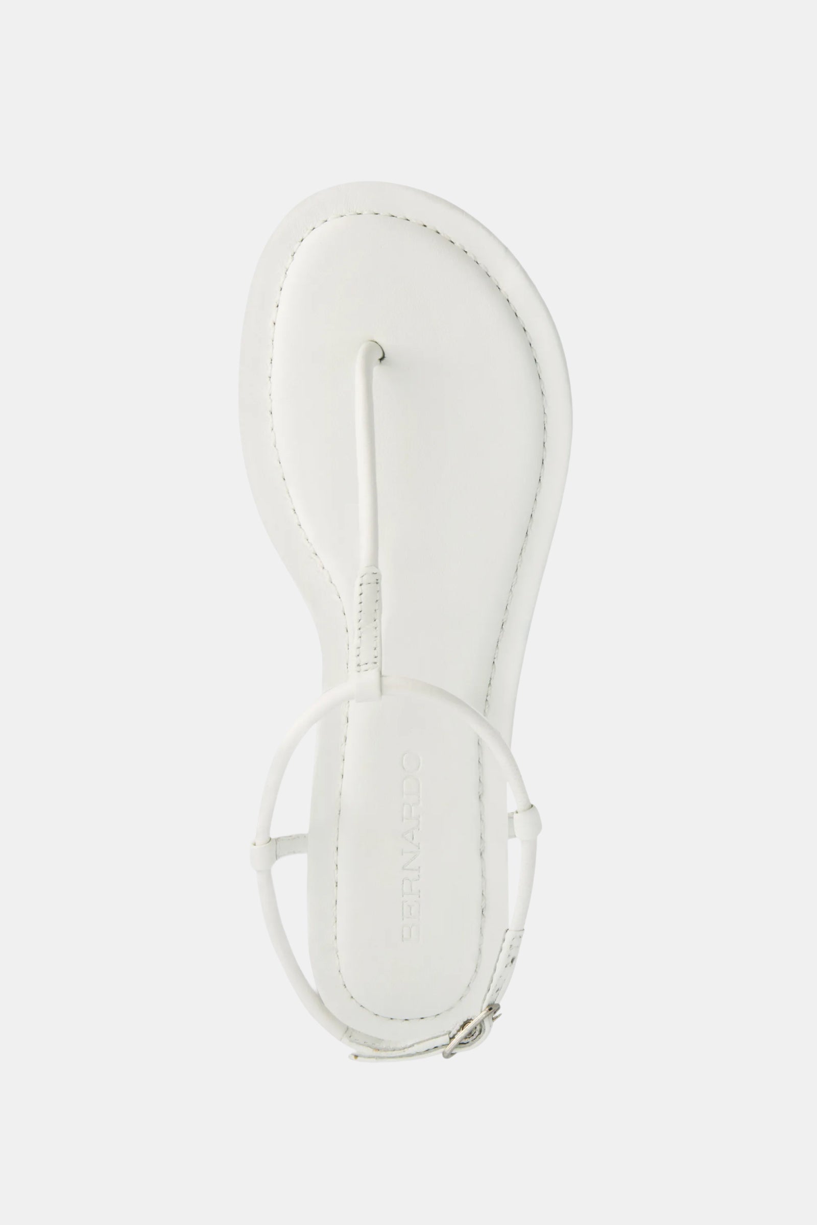 A top view of the Hercu Sandal, a white flat sandal featuring a single toe post, circular ankle strap, minimal stitching, and BERNARDO embossed on the insole.