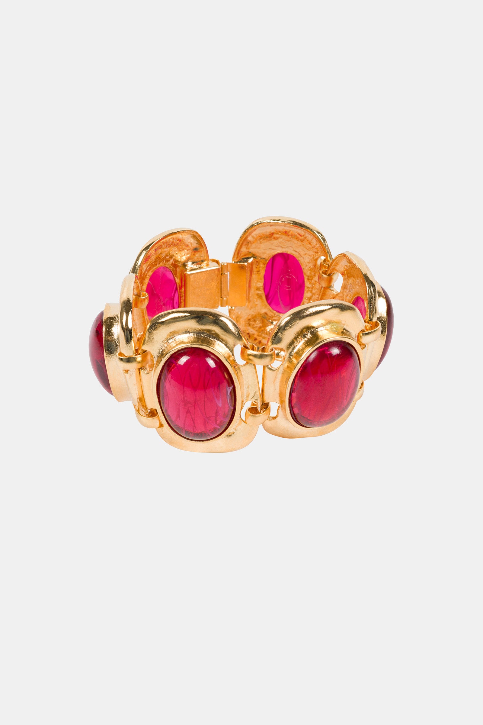 The Ruby Cabachon Bracelet features large oval ruby stones set in gold frames, linked together in a circular design, and is displayed on a plain white background.