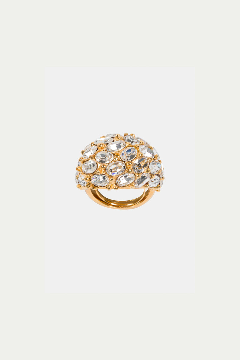 The Cluster Stone Dome Ring is a gold ring with a domed top, showcasing an intricate openwork design and multiple clear, oval and round gemstones. Its luxurious, ornate appearance stands out against a plain white background.