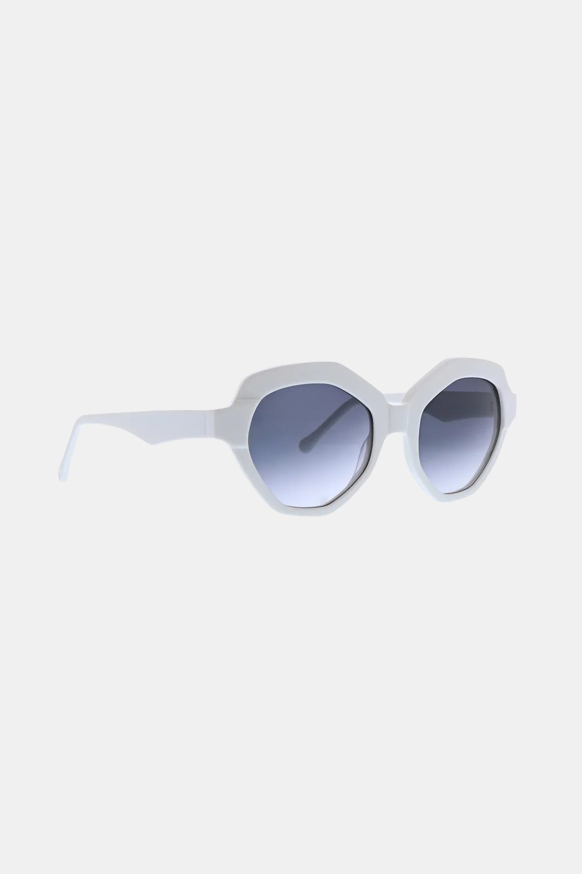 The Ipanema Sunglass features white octagonal frames with a thick design and gradient blue-tinted lenses, displayed angled to the right on a simple light background.