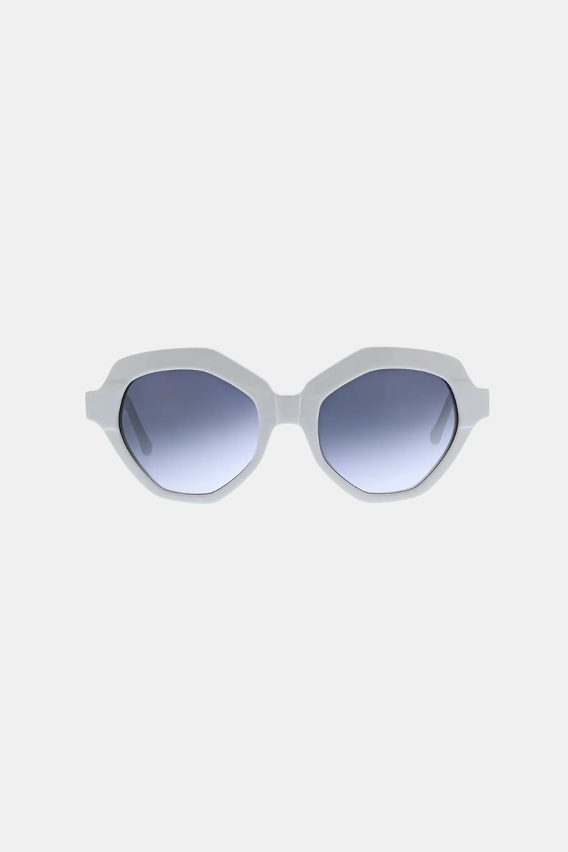 The Ipanema Sunglass features white, geometric-shaped thick frames and blue gradient lenses, showcased against a plain light gray background.