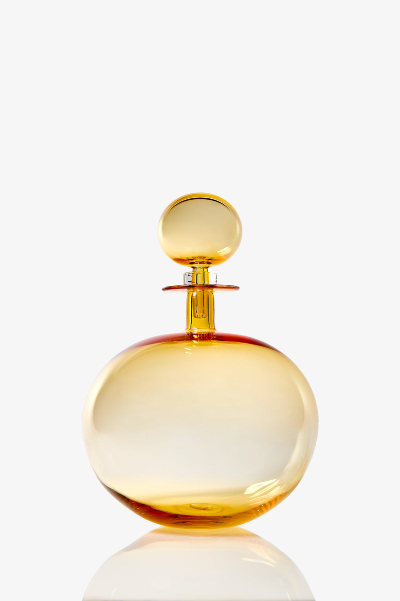 A large, round amber-colored glass decanter with a matching spherical stopper, set against a white background.