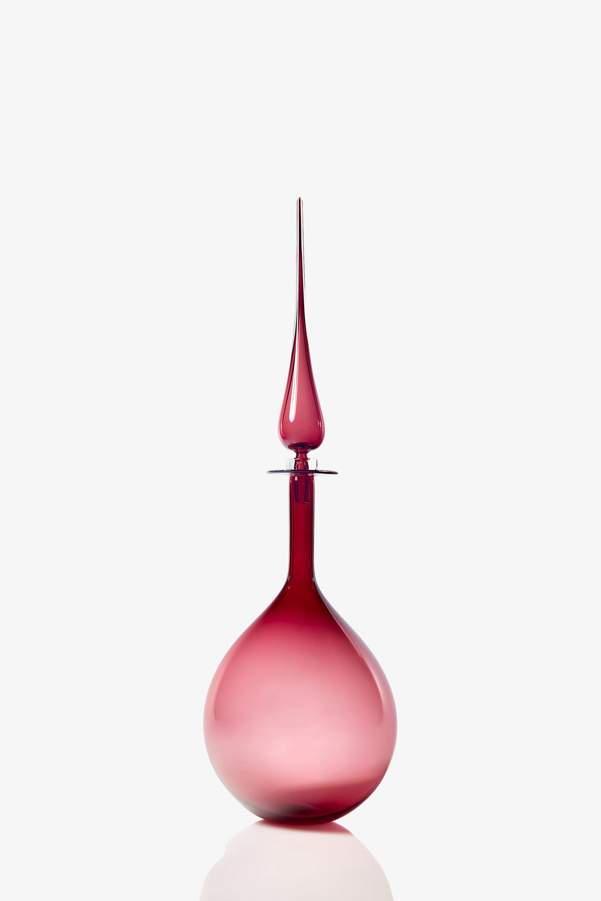 A Large Tear Drop Decanter, featuring a tall and elegant glass design with a round base and elongated stopper, displays a gradient pink to red color and is set against a white background.