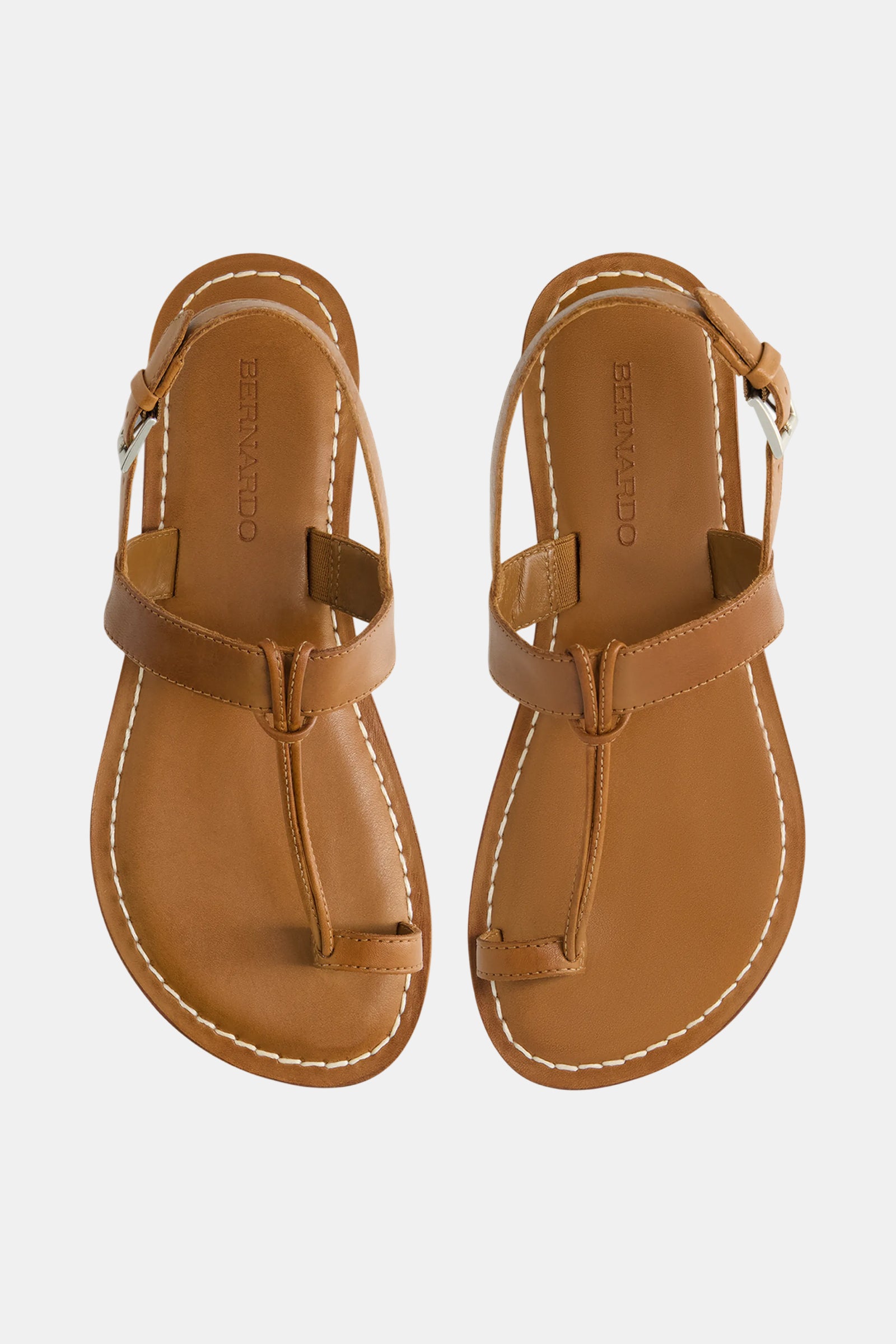 Bernardo Maverick 2 Sandal: brown leather sandals with a T-strap design and white edge stitching, shown on a white background.