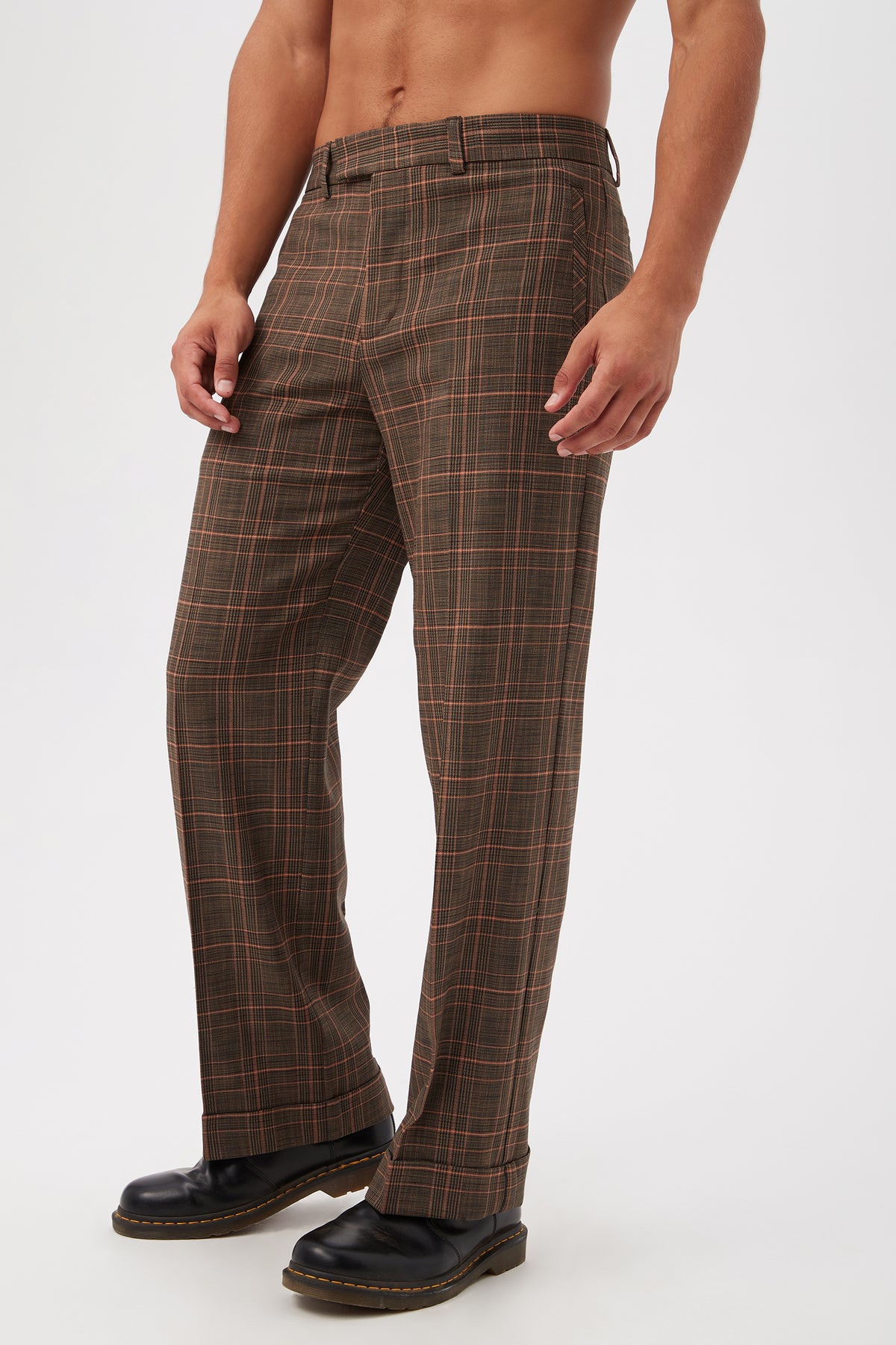 A shirtless man wearing Genet Wide-Leg Trousers - Chaka Check Plaid and black shoes, standing against a plain white background.